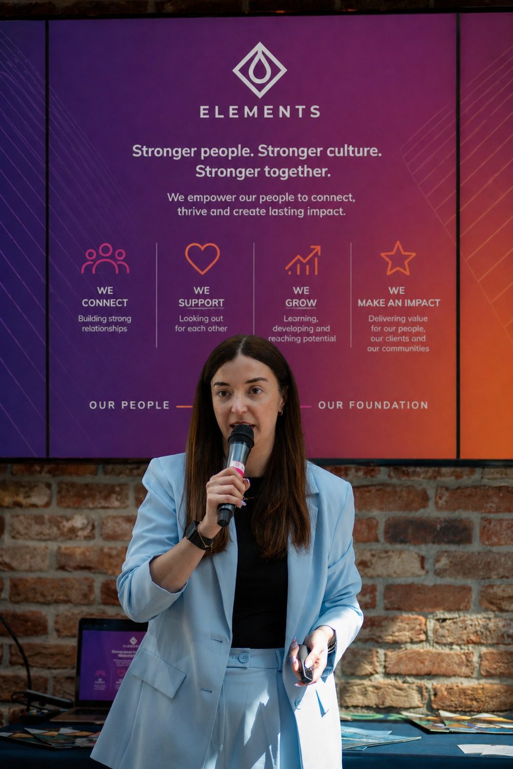 Therese Cullen, Founder and CEO of Elements, speaking at a company event in front of the Elements culture board